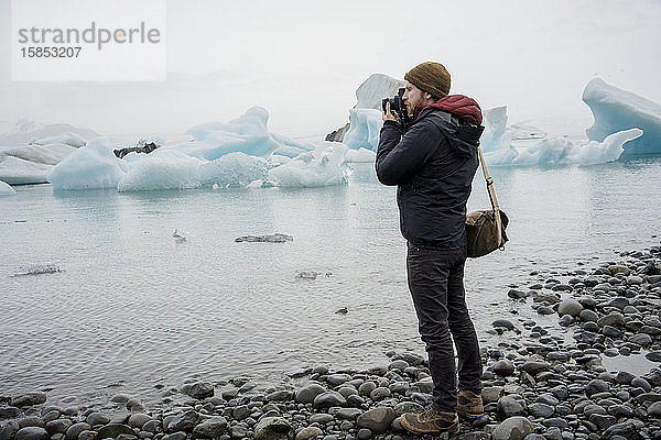 Mann fotografiert die Gletscherlagune Jokulsarlon in der Abenddämmerung