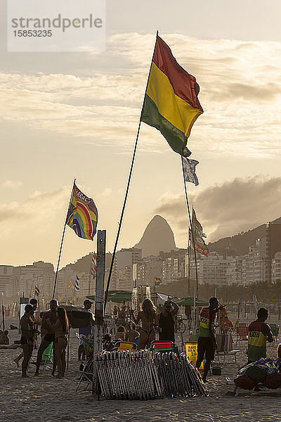 Schöne Aussicht auf Flaggen und Einheimische bei Sonnenuntergang am Copacabana-Strand