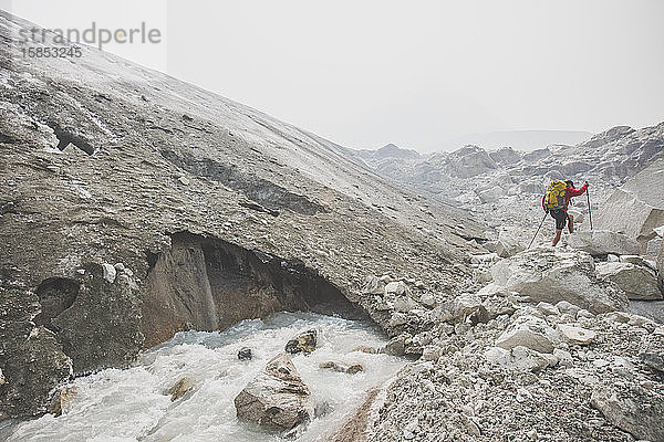 Rucksacktourist beim Wandern neben dem schmelzenden Gletscher.