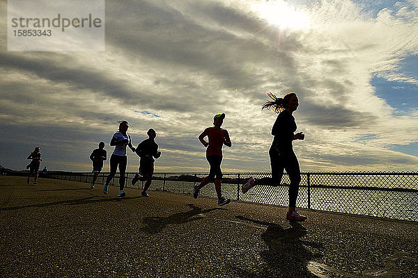 Eine Gruppe silhouettierter Läufer in der Nähe des Hafens von Boston.
