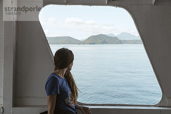 Seitenansicht einer Frau  die durch ein Bootsfenster hinaussieht