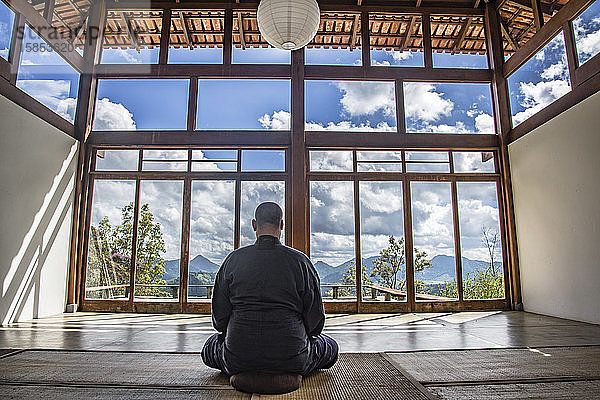 Mönch meditiert in einem Haus im japanischen Stil zwischen den Bergen
