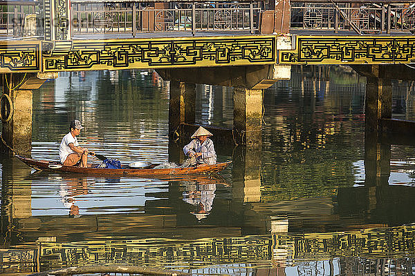 Zwei Personen fischen auf einem traditionellen vietnamesischen Holzboot in Hoi An.