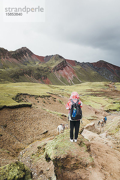 Eine junge Frau mit einem Rucksack steht auf einem Hügel in Peru