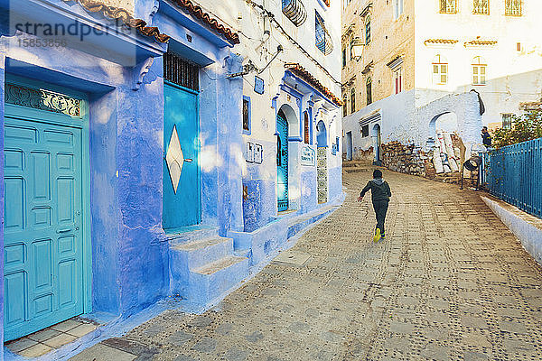 Einheimischer Junge rennt in der Straße des blauen Dorfes Chefchaouen