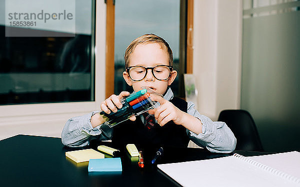 kleiner Junge  der in einem Büro arbeitet  während sein Vater ihm mit seinen Stiften hilft