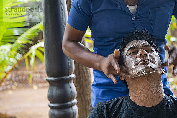 Mann erhält in Sri Lanka eine Ayurveda-Gesichtsbehandlung