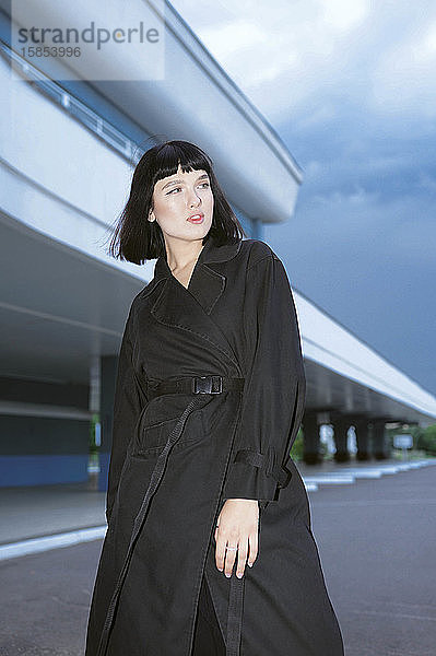 Frau in einem schwarzen langen Mantel am Bahnhof