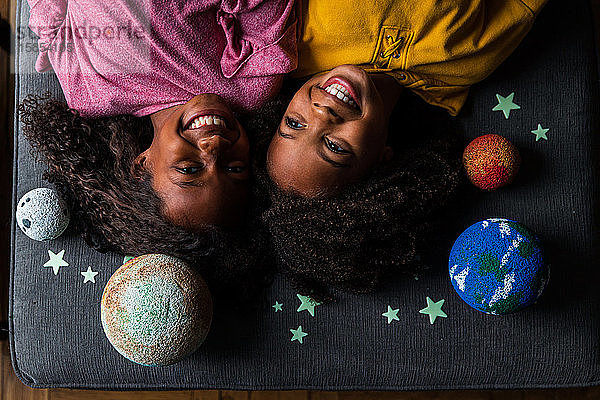 Draufsicht auf glückliche Schwestern  die am Sonnensystem liegen