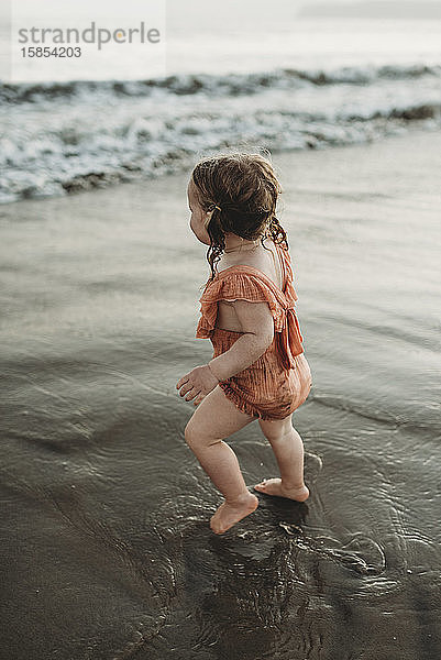 Junges Kleinkind mit Zöpfen geht in den Ozean