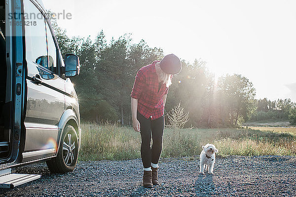 Frau  die im Sommer mit ihrem Hund spazieren geht  während sie in einem Wohnmobil zeltet