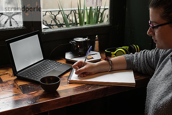 Junge Studentin lernt mit ihrem Laptop in einem Café