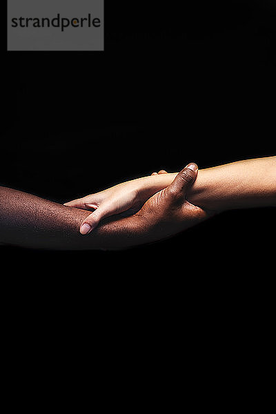 Männer- und Frauenhände mit unterschiedlichen Hauttönen halten sich gegenseitig