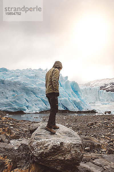 Unbekannter Mann auf Felsblock in Gletschernähe stehend