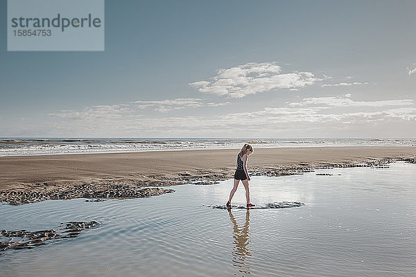 Junges Mädchen geht am Strand durchs Wasser
