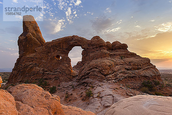 Silhouette eines Wanderers eingerahmt in Turret Arch bei Sonnenuntergang im Arches Park