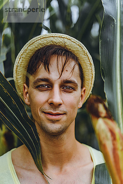 Porträt eines lächelnden Bauern mit Hut auf einer grünen Wiese.