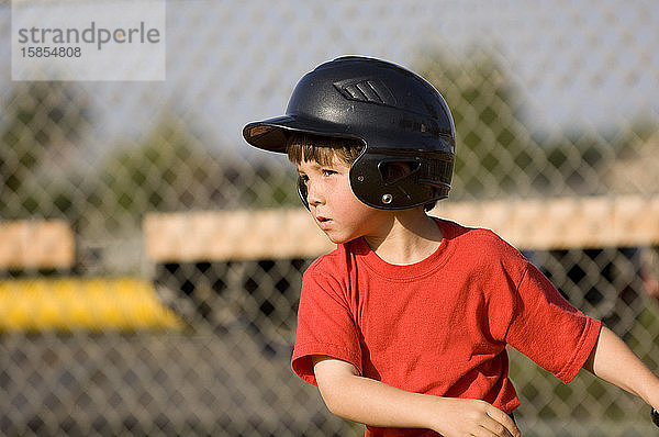 Junge mit Baseballhelm konzentriert sich auf seinen Treffer