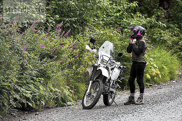 Eine Frau macht eine Pause vom Motorradfahren und nimmt ihren Helm ab.