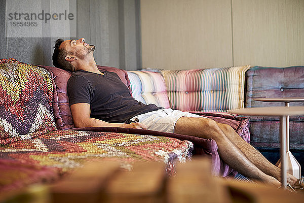 Ein Mann entspannt sich auf einer bequemen modernen Couch.