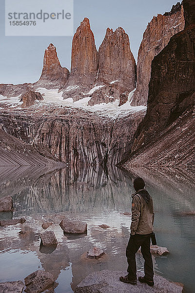 Wanderer steht in den Bergen in der Nähe eines ruhigen Sees
