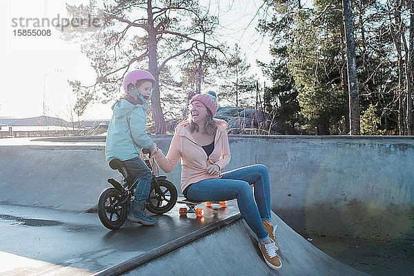 Mutter und Tochter spielen und lachen in einem Skatepark in der Sonne