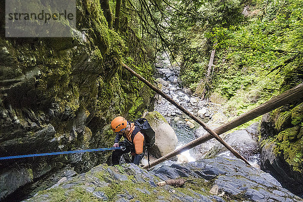 Mann  der sich neben einem Wasserfall im Frost Creek Canyon abseilt.