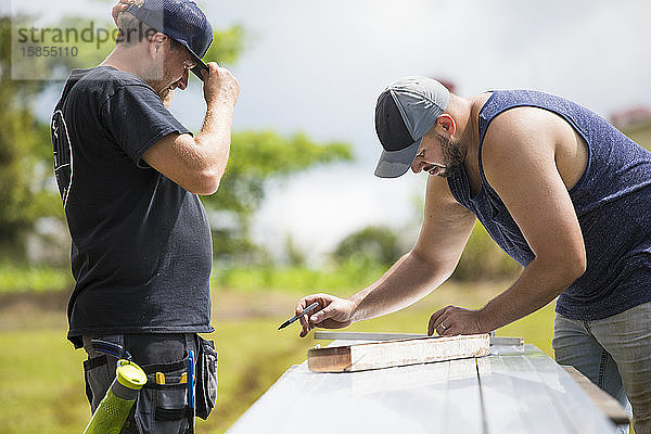 Zwei Männer messen Halterungen für die Installation von Solarpaneelen.