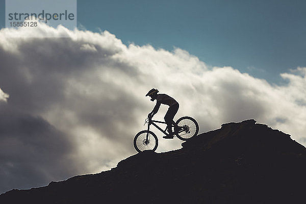 Seitenansicht eines jungen Mannes auf einem Mountainbike beim Fahren über Felsen in Utah