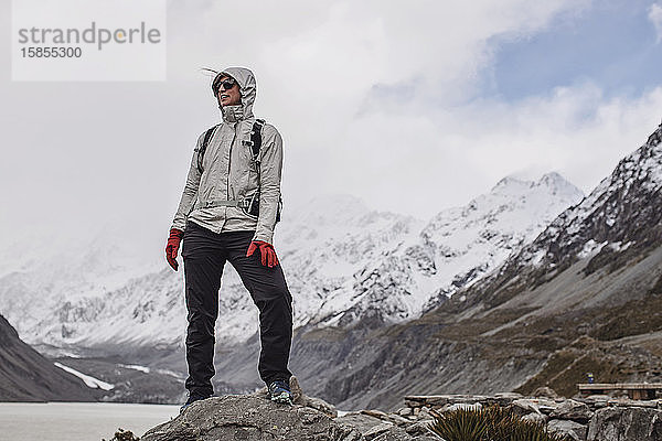 Kalte Frau steht auf Fels bei Wanderung ins Hooker Valley Neuseeland