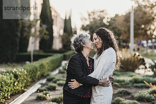 Aktive ältere Frau und erwachsene Tochter umarmen sich draußen