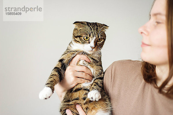 Junge Frau hält schöne Katze auf weißem Hintergrund