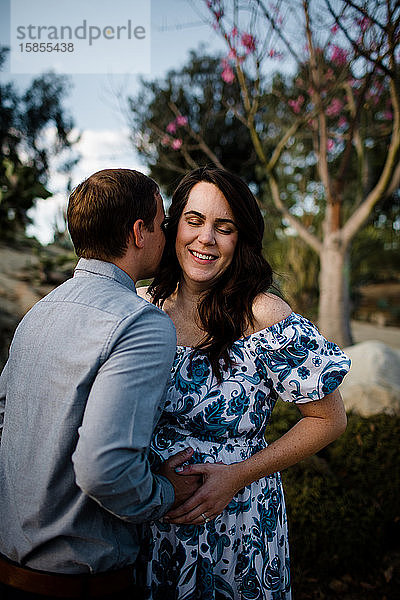 Ehemann umarmt schwangere Frau beim Lächeln