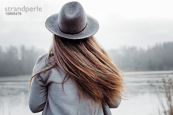 Der Haarrücken einer Frau  die im Winter am Strand im Wind weht