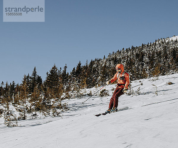 Eine Frau mit roten Skiern fuhr an einem kalten Morgen den Baldface Mountain in NH hinunter.