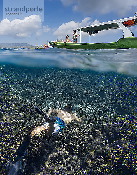 Junger Mann schnorchelt in der Nähe des Bootes im Meer  Unterwassersicht