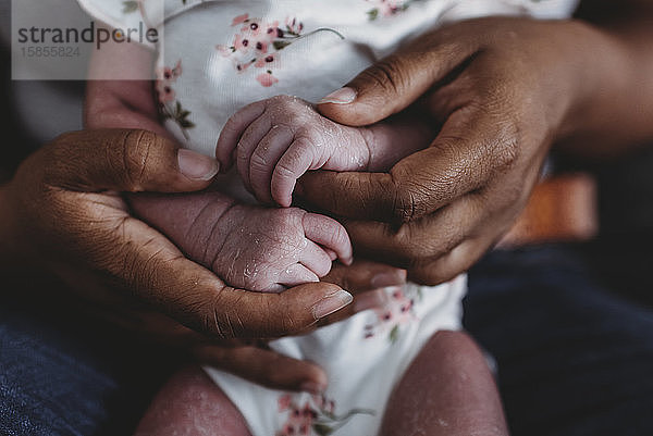 Ethnische Frauenhände halten winzige wachsartige Hände von Neugeborenen verschiedener Rassen