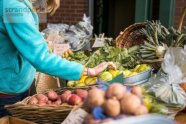 Junge Frau betrachtet Gemüse auf dem Bauernmarkt