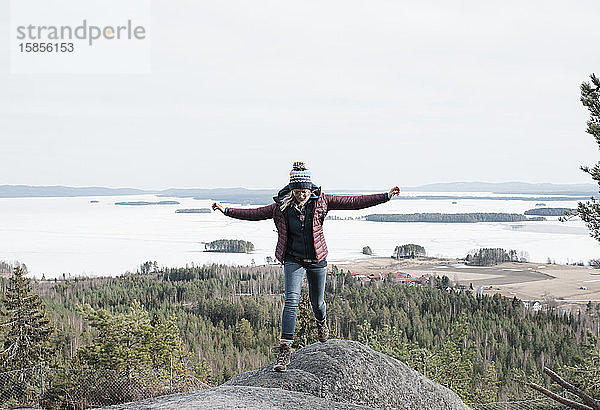 Frau springt über Felsen  während sie in Schweden einen Berg hinaufwandert