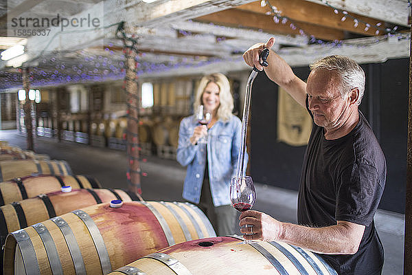 Ein Sommelier extrahiert während einer Weintour Wein aus einem Fass.