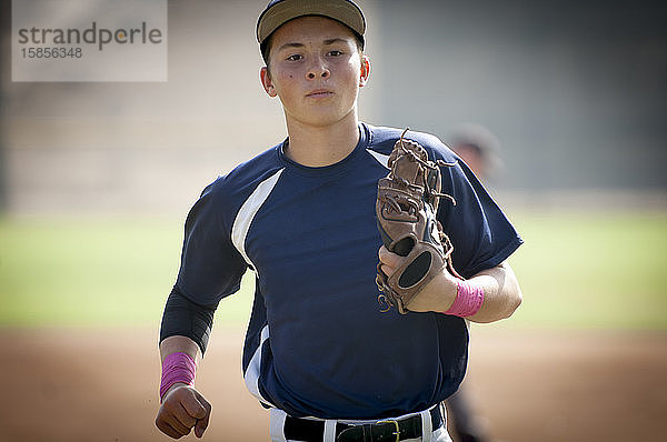 Nahaufnahme eines jugendlichen Baseball-Spielers in blauer Uniform  der vom Spielfeld joggt