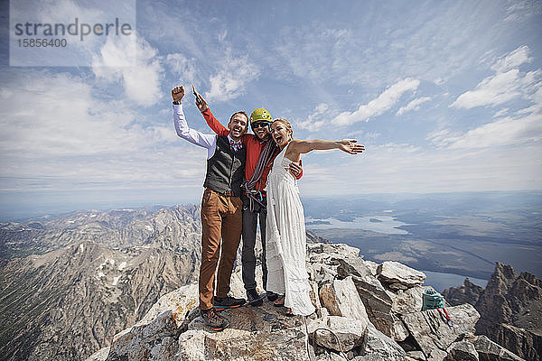 Neuvermähltes Brautpaar feiert mit Kletterführer auf dem Berggipfel