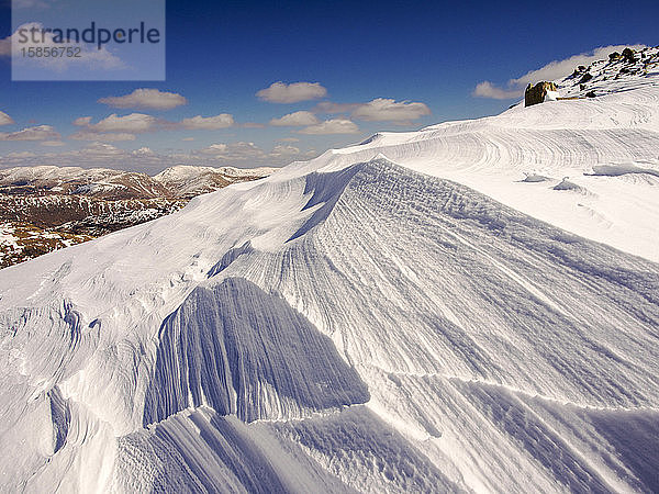 Schnee  der bei seinem Sturz über dem Wrynose Pass im Lake District  Cumbria  Großbritannien  von einem starken Wind geformt und weggeweht wurde.