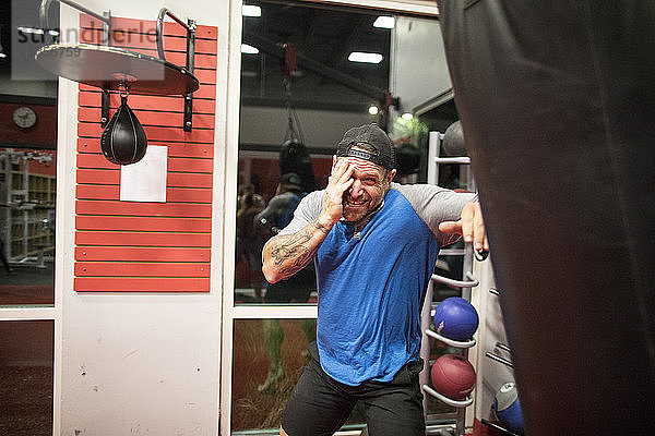 Kickboxer schützt sein Gesicht beim Training am Sandsack