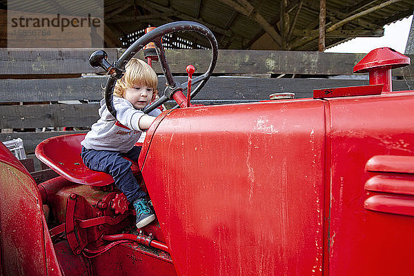 ein kleiner Junge  der sich auf einem roten Ackerschlepper amüsiert  Lomener  Bretagne  Frankreich.
