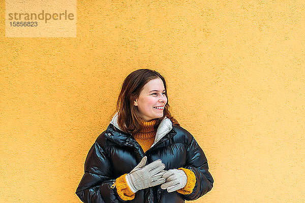 Junge Frau an gelber Wand stehend