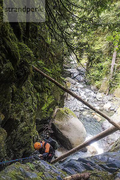 Hoher Winkel eines Mannes  der sich neben einem Wasserfall im Frost Creek Canyon abseilt.