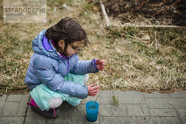 Ein kleines Kind legt zärtlich einen winzigen Baumsprössling in eine Tasse Wasser