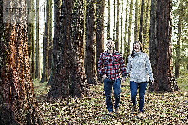 attraktives Paar  das durch den Wald geht und nach vorne schaut.