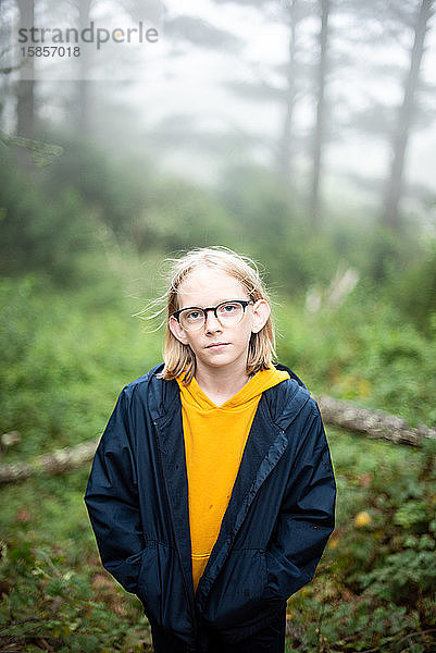 Porträt eines Jungen  der im Wald in die Kamera schaut